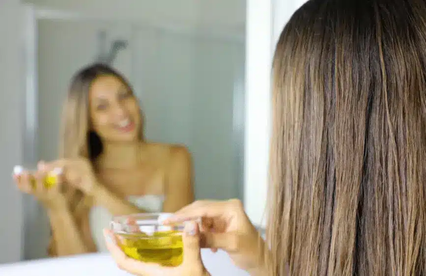 A young woman applying a mix of carrier oils for hair.