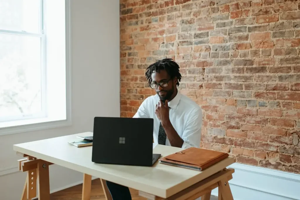 A man seated at a desk, focused on his laptop, comparing Panviva and Live Pro software solutions.