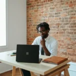 A man seated at a desk, focused on his laptop, comparing Panviva and Live Pro software solutions.